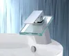 A modern chrome and glass waterfall faucet is installed on a white sink. Produktbild-Vorschau
