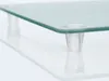 A close-up of a glass cutting board with clear plastic feet, resting on a reflective surface. Anteprima dell’immagine prodotto