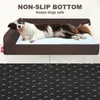 A dog is lying on a brown dog bed with a white cushion. The bottom of the dog bed is shown with a non-slip texture. Náhled obrázku produktu