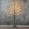 A decorative LED tree with white lights against a textured gray wall and wooden floor. Produktbild-Vorschau