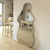 A large, irregularly shaped mirror leaning against a wall in a modern dining room and kitchen area. Produktbild-Vorschau