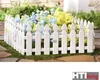 A white picket fence surrounding flowers in a garden. Produktbild-Vorschau