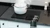 A pot of steaming food is on a black glass stovetop. Anteprima dell’immagine prodotto