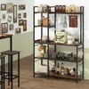 A kitchen shelf unit with various items on it, including coffee makers, jars, bottles, and decorative items. There are also framed pictures on the wall behind it and bar stools in the foreground. Voir les images du produit