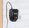 A black battery charger is mounted on a white brick wall. Produktbild-Vorschau
