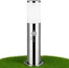 A silver outdoor lamp with a motion sensor stands on green grass against a white background. Produktbild-Vorschau