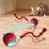 A cat is playing with a red interactive LED ball toy on a wooden floor. Náhled obrázku produktu