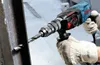 A person wearing work gloves is using a Bosch hammer drill to drill into a metal beam. Náhled obrázku produktu