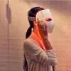 A woman is holding a white LED face mask to her face, with red light emitting from the mask. Anteprima dell’immagine prodotto
