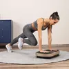 A woman is exercising on a vibration plate in a room. Náhled obrázku produktu