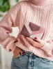 A person wearing a pink sweater and jeans holds a multi-colored wallet. Podgląd zdjęcia produktu