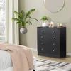 A black dresser with gold knobs sits next to a window with sheer curtains. A large potted plant is in the foreground. Náhľad obrázku produktu