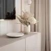 A close-up view of a decorative arrangement on a cabinet, featuring a vase of dried flowers and a marble-patterned dish. Produktbild-Vorschau