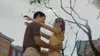 A couple hugging outdoors with trees and buildings in the background. Anteprima dell’immagine prodotto
