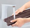 Hands washing a brown door draft stopper under a faucet. Náhled obrázku produktu