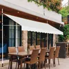 An outdoor patio area with tables and chairs set up under a white awning. Anteprima dell’immagine prodotto