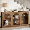 A wooden console table with arched compartments, styled with decorative items and books, placed near a staircase. Voir les images du produit