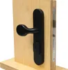 A black door handle set with a keyhole escutcheon mounted on a wooden board, showing the lock mechanism on the side. Produktbild-Vorschau