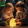 Two young children are sitting on the floor, looking at a glowing capybara-shaped night light. Náhled obrázku produktu