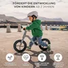 A young boy is riding a balance bike outdoors by the water. Produktbild-Vorschau