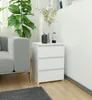 A white bedside table with three drawers is placed next to a grey sofa in a living room setting. A plant and decorative vases are on top of the table. Produktbild-Vorschau