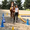 A woman and a horse in an outdoor arena with training equipment. Náhľad obrázku produktu