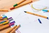 A notebook with math diagrams and writing, surrounded by colorful pens and a protractor. Produktbild-Vorschau