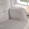 Close-up view of a light gray corduroy armchair, showing the texture and stitching. A window and a round wooden table are visible in the background. Anteprima dell’immagine prodotto