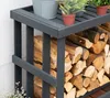 A close-up view of a dark gray wooden log rack filled with firewood, with potted plants on top. Podgląd zdjęcia produktu