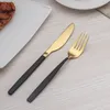 A set of cutlery, including a knife and fork, is placed on a light-colored wooden surface next to a white plate with a piece of steak. Produktbild-Vorschau