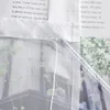 A close-up view of a sheer curtain with a floral pattern and text printed on paper behind it. Produktbild-Vorschau