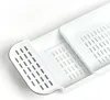 A close-up, angled view of a white plastic bath caddy with drainage slots. Náhled obrázku produktu
