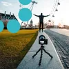 A camera on a tripod is set up to film a person standing with their arms outstretched in front of the London Eye. Produktbild-Vorschau