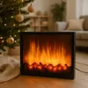 A decorative electric fireplace with LED flames sits on a wooden floor next to a Christmas tree with ornaments and lights. Náhled obrázku produktu