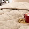 A close-up of a beige comforter with a red mug of coffee and biscotti on it. Produktbild-Vorschau