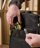 A person's hands are shown interacting with a tool bag, placing a small yellow and black digital measuring device into a pocket. Anteprima dell’immagine prodotto