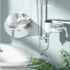 A close-up view of a water heater faucet attachment installed on a bathroom wall, with a sink in the foreground. Produktbild-Vorschau