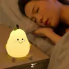 A pear-shaped LED night light sits on a nightstand next to a sleeping person. Produktbild-Vorschau