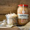 Two jars of sauerkraut are displayed on a wooden surface with a rustic background. Produktbild-Vorschau