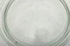A close-up view of the embossed text and logo on the lid of a glass jar. Produktbild-Vorschau