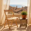 A wooden chair and a plant on a balcony overlooking the sea and rooftops. Produktbild-Vorschau