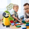 A father and son are playing with building blocks on the floor, with a plush parrot toy in the foreground. Anteprima dell’immagine prodotto