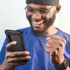 A man is happily looking at his phone, which is in a protective case. Podgląd zdjęcia produktu