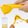 A yellow manual citrus juicer is shown in two actions: juicing a lemon into a glass and demonstrating its folding mechanism. Produktbild-Vorschau