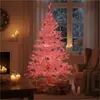 A pink artificial Christmas tree decorated with lights and ornaments, set in a cozy room with presents underneath and candles on a table. Produktbild-Vorschau