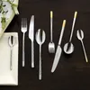 A collection of silverware laid out on a dark wooden surface. Produktbild-Vorschau