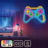 A neon gamepad sign is mounted on a brick wall above a desk with a computer monitor and a small speaker. Produktbild-Vorschau