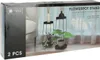 The image shows the packaging for a set of two black metal flowerpot stands. The packaging displays a lifestyle image of the stands with plants and decorative items in a home setting. Produktbild-Vorschau