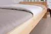 A close-up view of a wooden bed frame with bedding. Produktbild-Vorschau