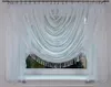 A white sheer curtain with beaded fringe is draped across a window. Produktbild-Vorschau
